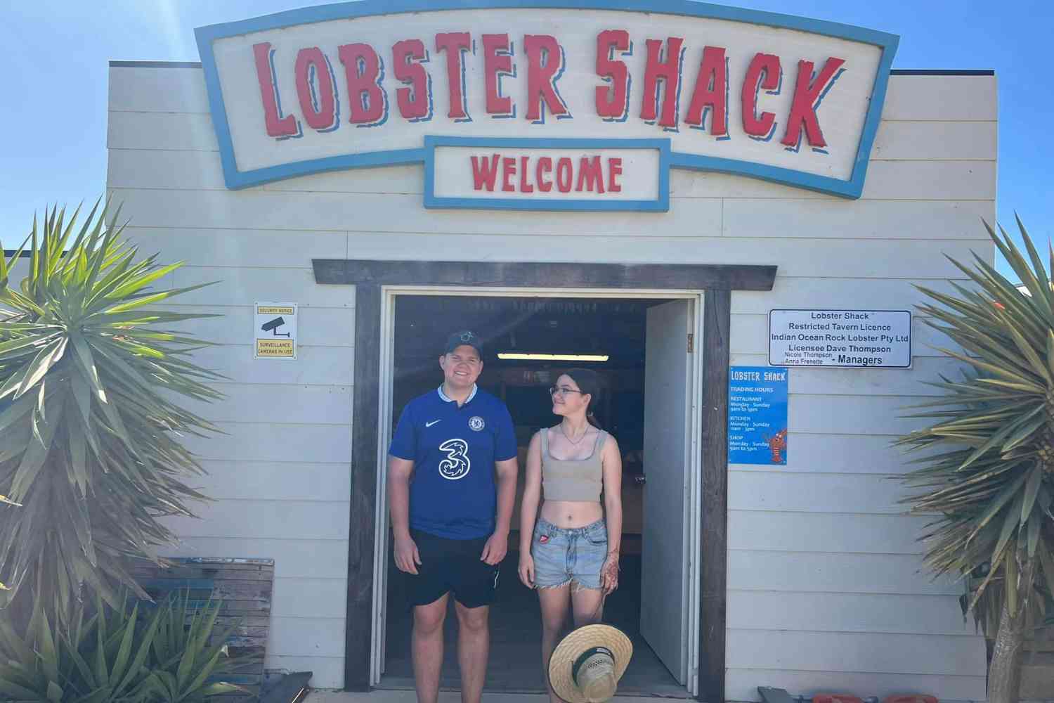 Two teenagers stand in the doorway of the Lobster Shack in Cervantes Western Australia. They look happy. 